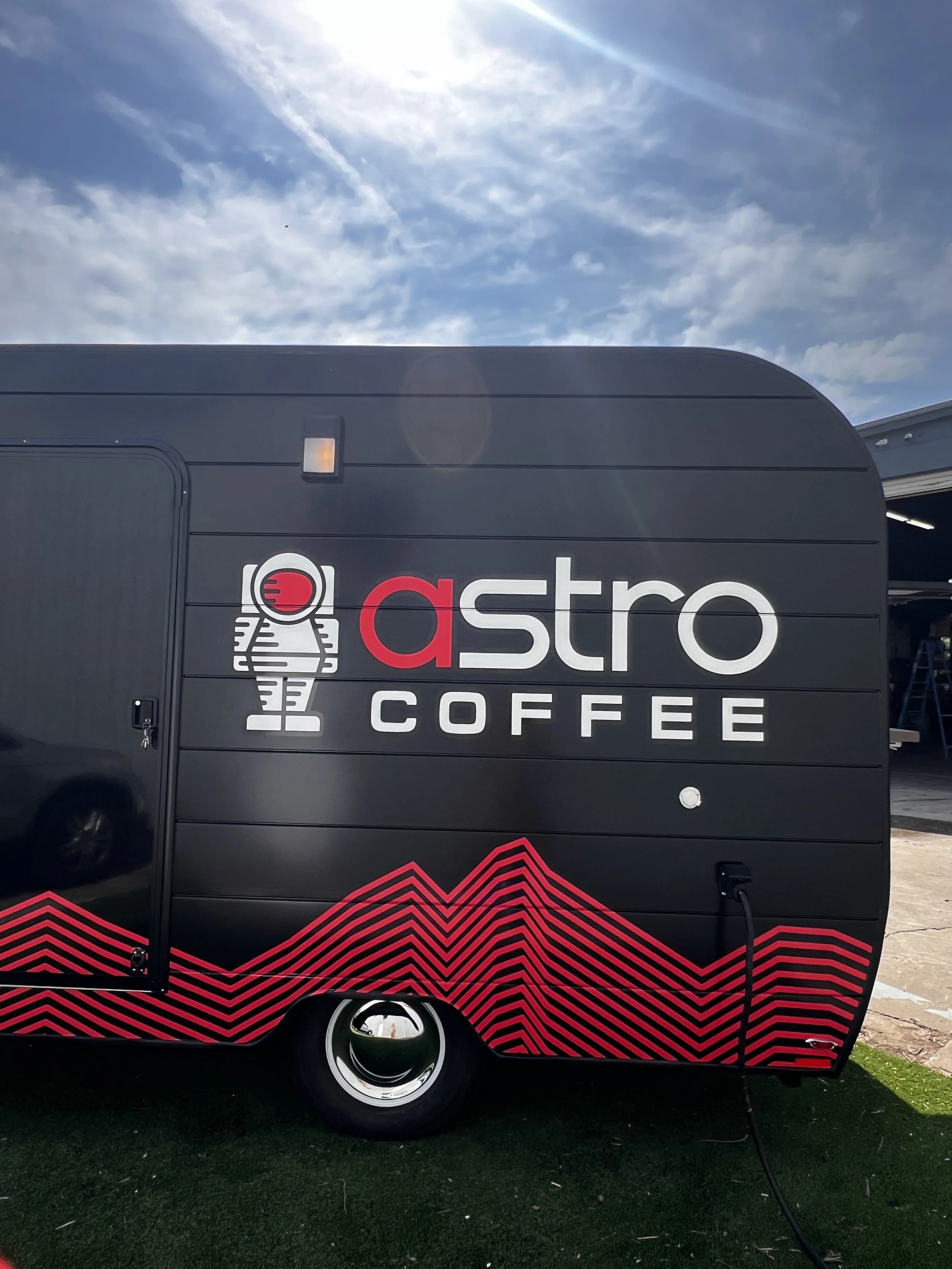 Black and red Astro Coffee mobile bar with its service window open